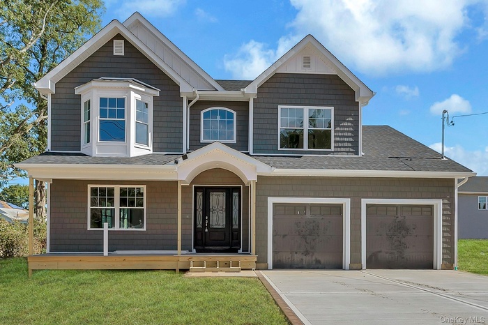 View of front of home with a shingled roof, concrete driveway, and a front yard