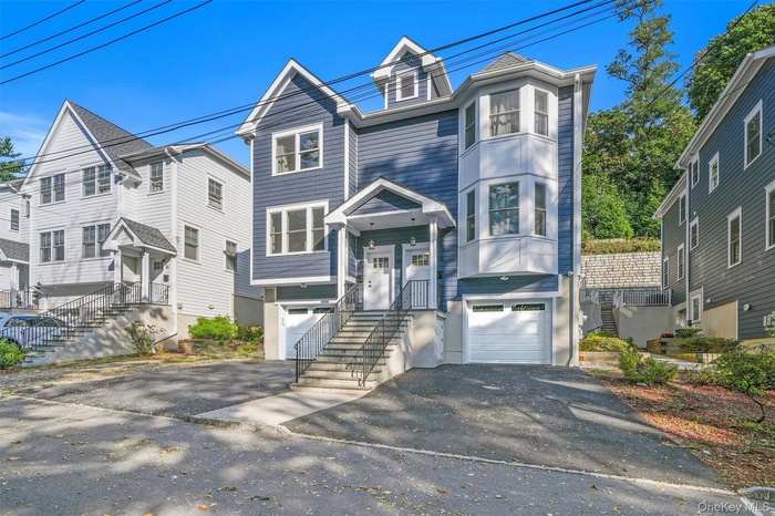 View of front facade with asphalt driveway, an attached garage, and a residential view