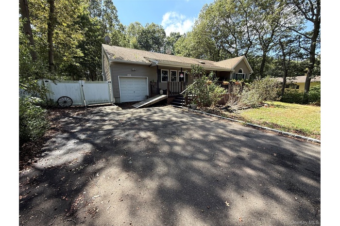 View of front of home featuring a gate, a garage, a wooden deck, and asphalt driveway