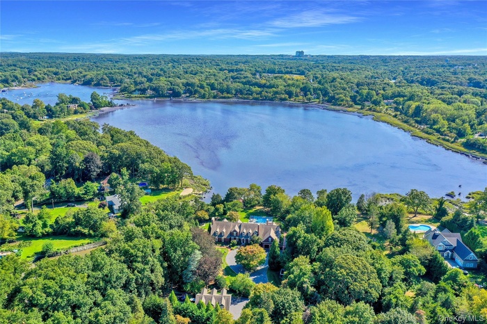 Aerial view of property's location featuring a forest and a nearby body of water