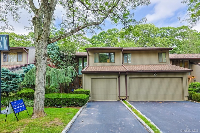 View of front facade featuring a shingled roof, an attached garage, and driveway