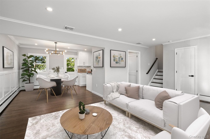 Living area featuring crown molding, dark wood-style floors, a chandelier, recessed lighting, and stairs- Virtually Staged