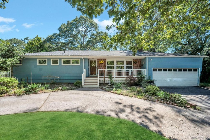 Ranch-style house with driveway, an attached garage, covered porch, and roof with shingles