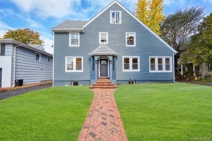 View of front facade with a front lawn and a shingled roof