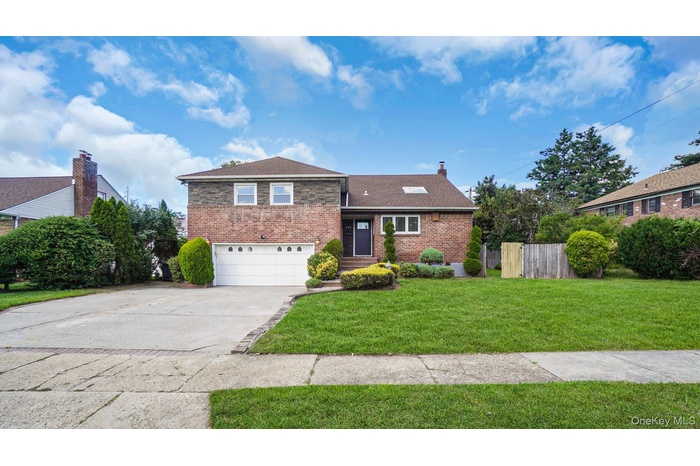 Tri-level home featuring brick siding, concrete driveway, an attached garage, a chimney, and roof with shingles