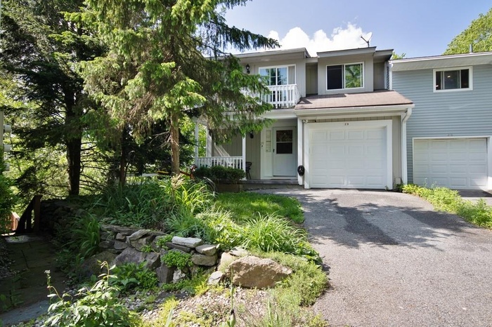 View of front of property featuring a garage, driveway, a balcony, and covered porch
