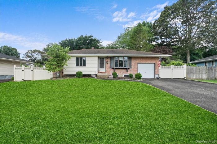 Ranch-style house featuring a gate, driveway, an attached garage, and brick siding