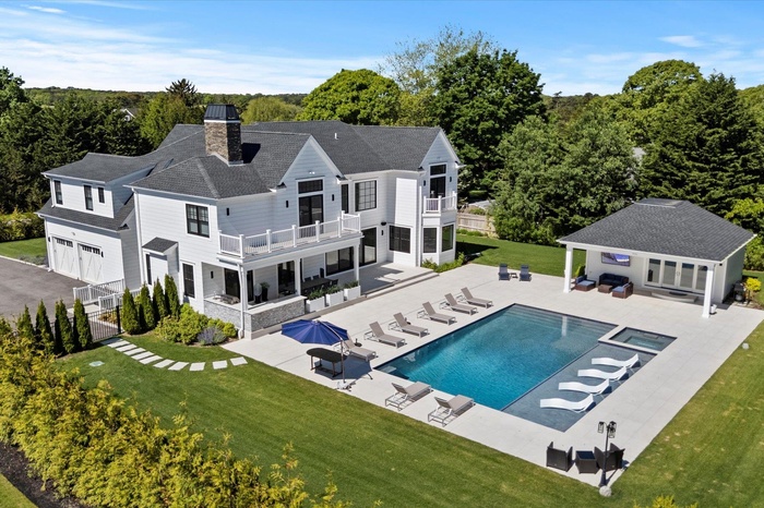 Rear view of property featuring a balcony, a lawn, an outbuilding, an outdoor hangout area, and a patio