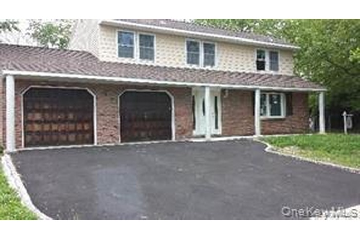 Traditional-style home with driveway, covered porch, and an attached garage