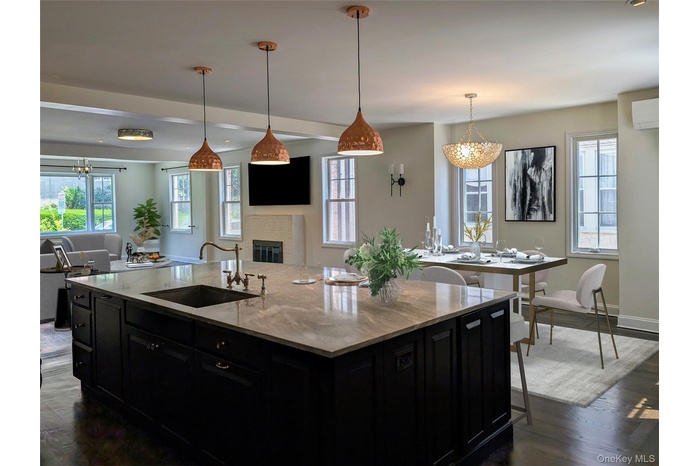 Kitchen with dark cabinets, a chandelier, dark wood-style flooring, and open floor plan