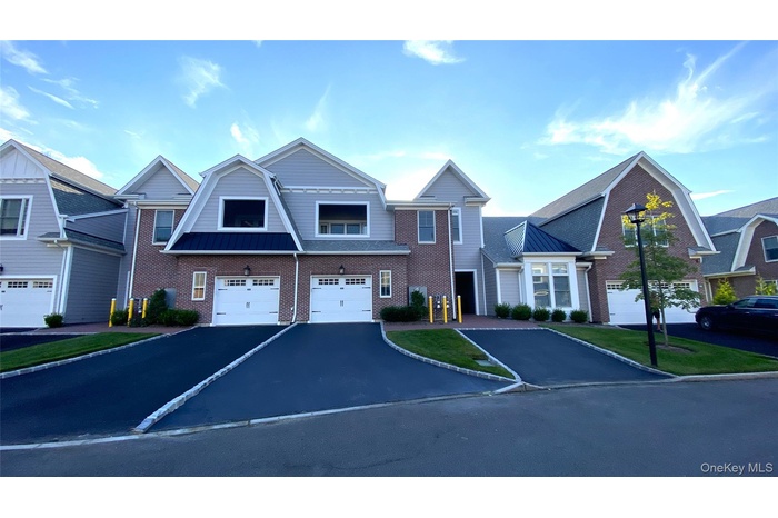 View of front of home featuring a gambrel roof, driveway, brick siding, a standing seam roof, and a metal roof