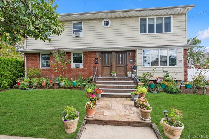 Colonial home with a front yard and brick siding