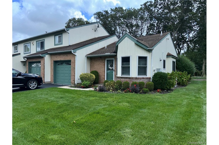 View of front of property featuring a garage, a front lawn, brick siding, and asphalt driveway