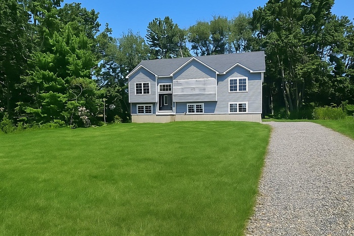Raised ranch with a front yard and view of scattered trees