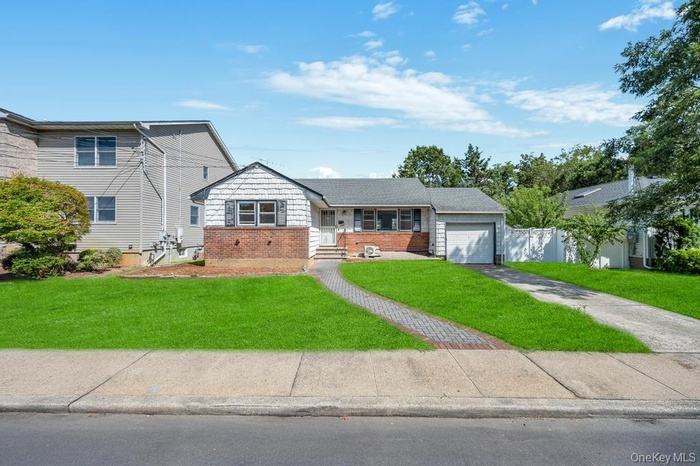 View of front of house featuring brick siding, driveway, a garage, and a front yard