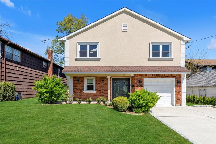 Traditional-style home featuring brick siding, a front lawn, an attached garage, and driveway