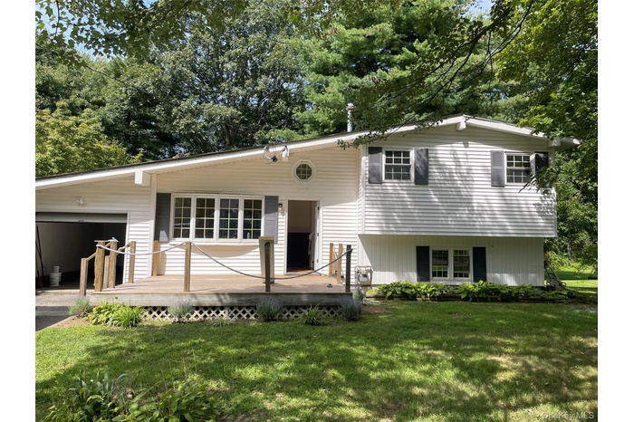 View of front of property with an attached garage, a front lawn, and a wooden deck