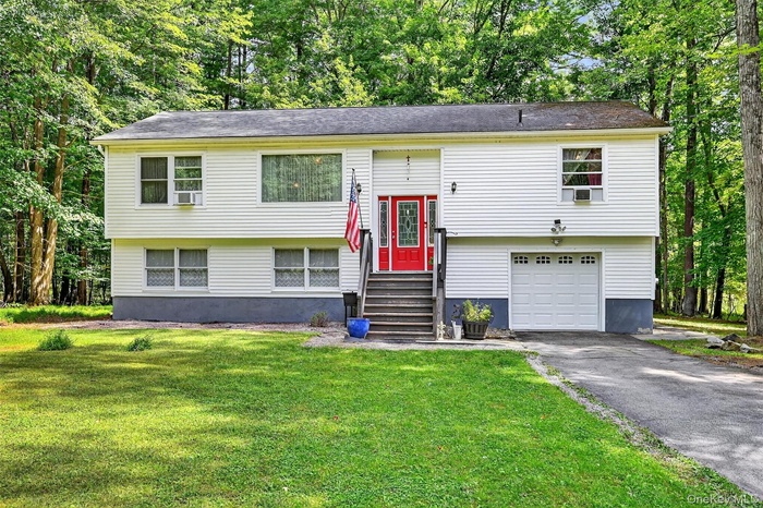 Bi-level home featuring a garage, asphalt driveway, a front lawn, and entry steps