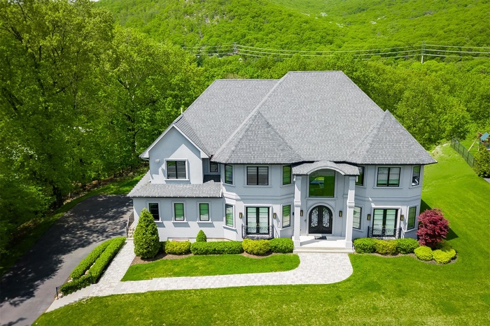 View of front of property with french doors, stucco siding, and a wooded view