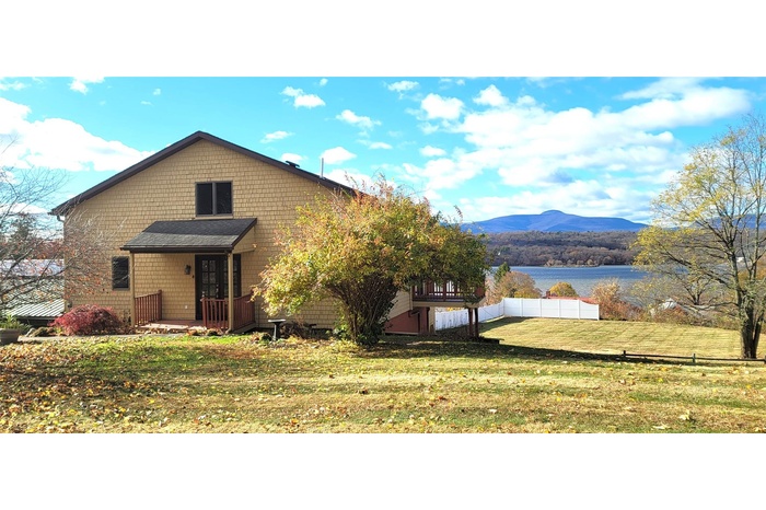 View of front facade with a water and mountain view and a front yard