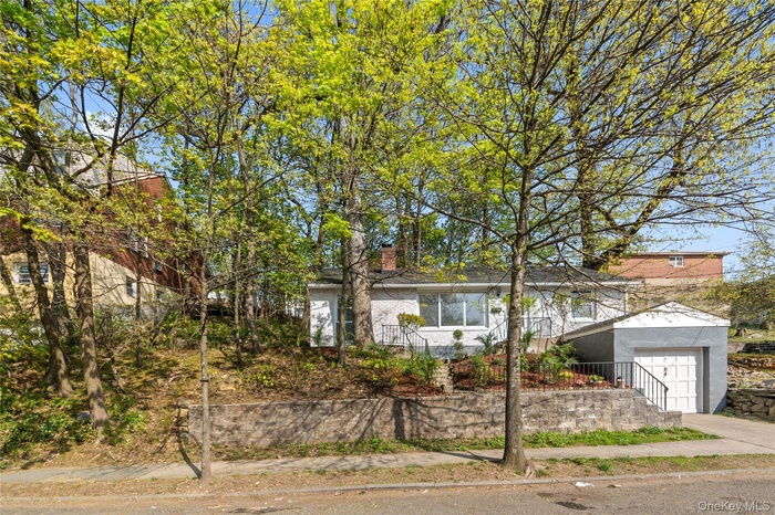 View of front of house with driveway, an attached garage, and a chimney