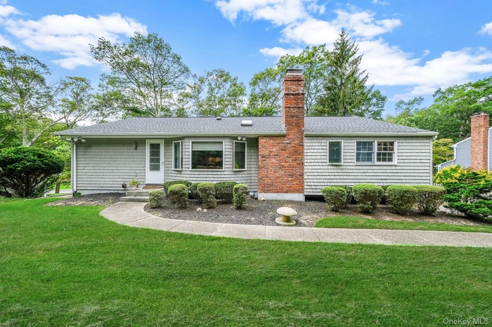 Front view of property featuring a lawn, a chimney, and a shingled roof