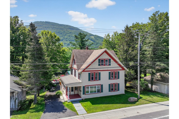 View of front of property featuring a front yard, a chimney, asphalt driveway, a mountain view, and covered porch