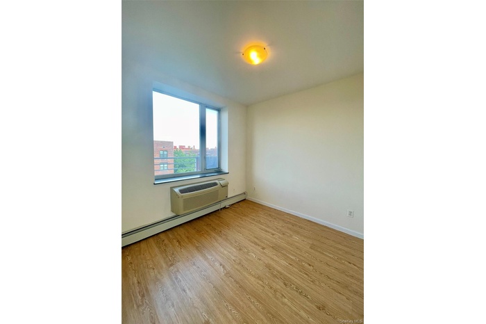 Spare room featuring light wood finished floors, a baseboard radiator, and a wall unit AC