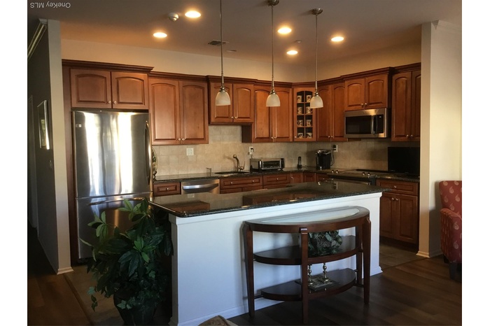 Kitchen with appliances with stainless steel finishes, dark stone counters, decorative light fixtures, decorative backsplash, and dark wood-type floor