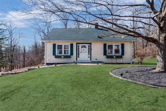 View of front of house with a front yard and roof with shingles