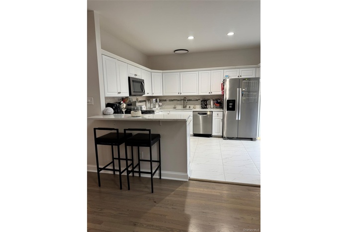 Kitchen featuring tasteful backsplash, appliances with stainless steel finishes, a peninsula, and white cabinetry