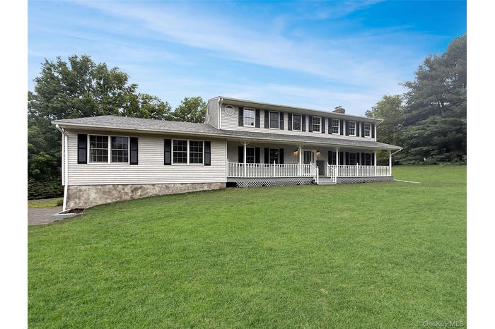 View of front of home with a front yard, a porch, and a chimney