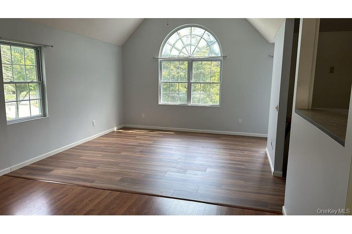 Unfurnished room with vaulted ceiling and dark wood-style flooring