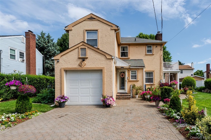 Traditional-style home with decorative driveway, a garage, stucco siding, and a chimney