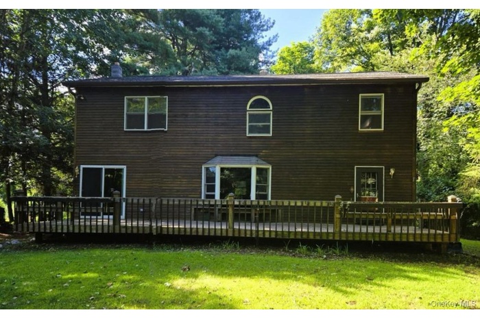 Back of house with a deck, a yard, and a chimney