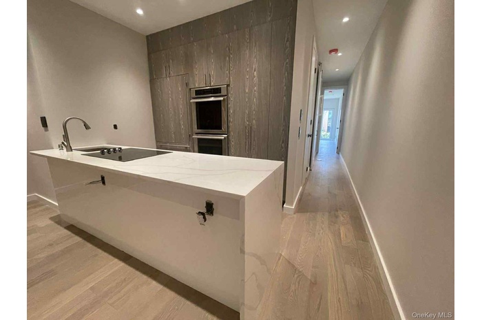 Kitchen featuring light stone countertops, recessed lighting, light wood finished floors, modern cabinets, and double oven