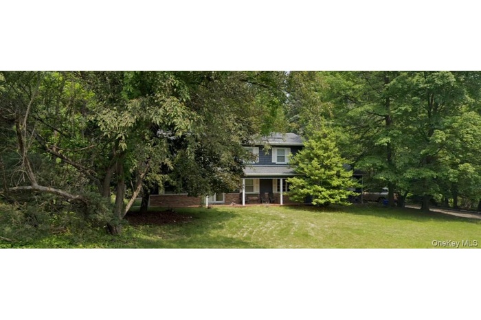 View of front of house with brick siding, a porch, and a front lawn
