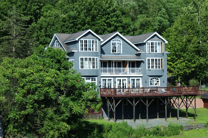 Back of house featuring a wooded view, a wooden deck, and french doors