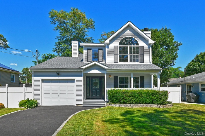Traditional-style home featuring a chimney, covered porch, asphalt driveway, and a garage