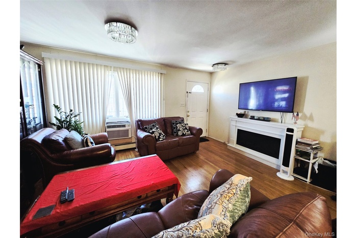 Living area with wood finished floors, baseboard heating, and a fireplace