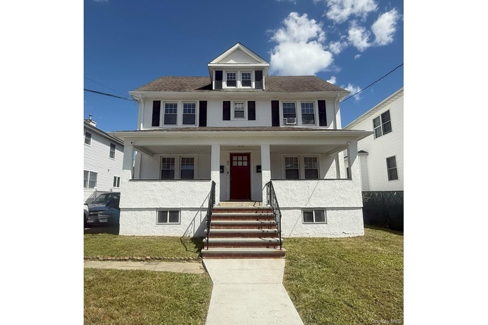 Traditional style home featuring a front lawn, a porch, stucco siding, and stairway