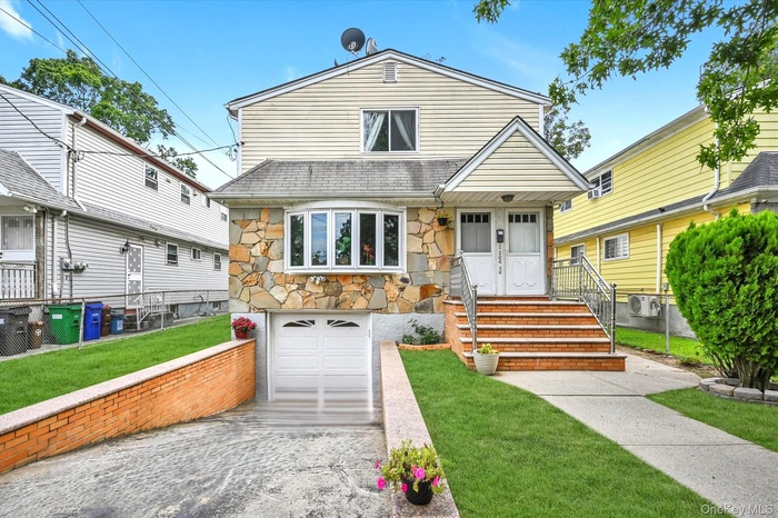 View of front of house with stone siding, an attached garage, and a front yard