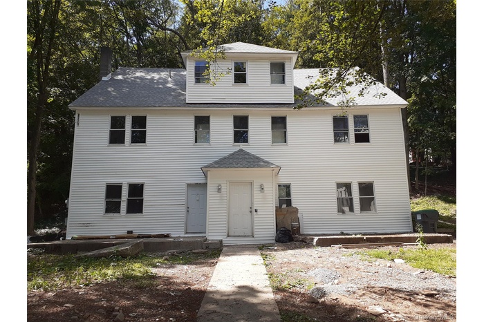 View of front facade with a shingled roof and a chimney