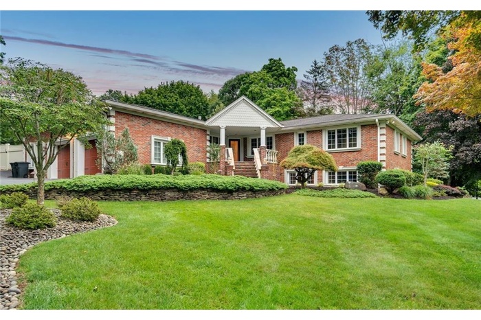 View of front of property with brick siding, a front lawn, an attached garage, and a porch