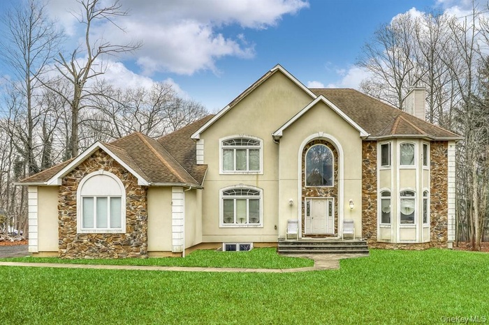 Traditional-style home featuring stone siding, a shingled roof, and stucco siding