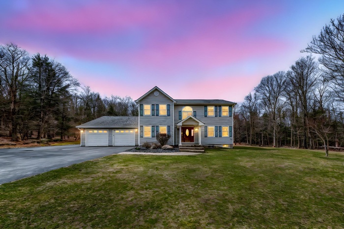 View of front facade with driveway, a garage, and a yard
