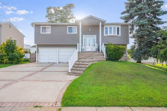 Split foyer home with a front lawn, concrete driveway, and an attached garage