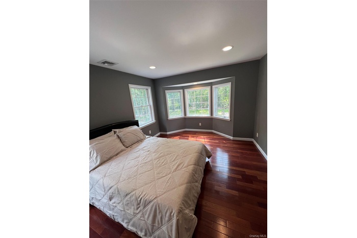 Bedroom with multiple windows, dark wood-type flooring, and recessed lighting