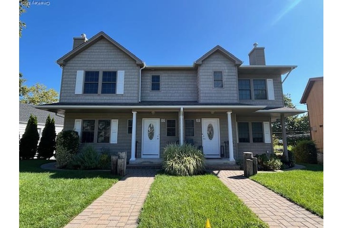 View of front of property with a chimney, a front yard, and covered porch