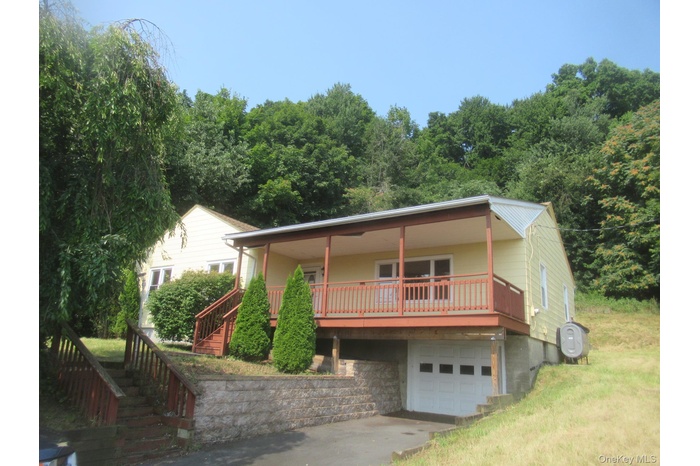 View of front of home featuring a porch, stairway, driveway, an attached garage, and heating fuel
